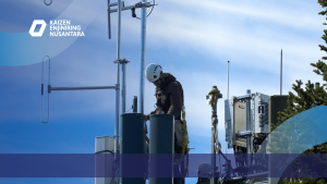 Teknisi sedang bekerja di atas tower telekomunikasi dalam proses instalasi perangkat, menggambarkan Perbedaan Perencanaan Tower 4G dan 5G dari sudut pandang konsultan Kaizen Enjiniring Nusantara.