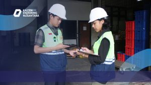 Tenaga Ahli dari PT. Kaizen Enjiniring Nusantara Sedang di lapangan mengenakan helm dan rompi keselamatan sedang melakukan pengecekan dokumen di area proyek konstruksi.